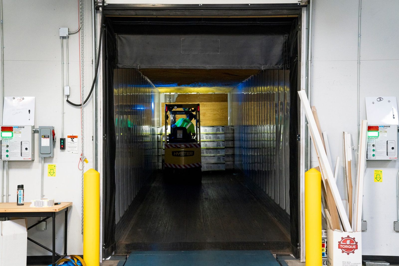 Forklift loading a temperature-controlled trailer at a warehouse dock